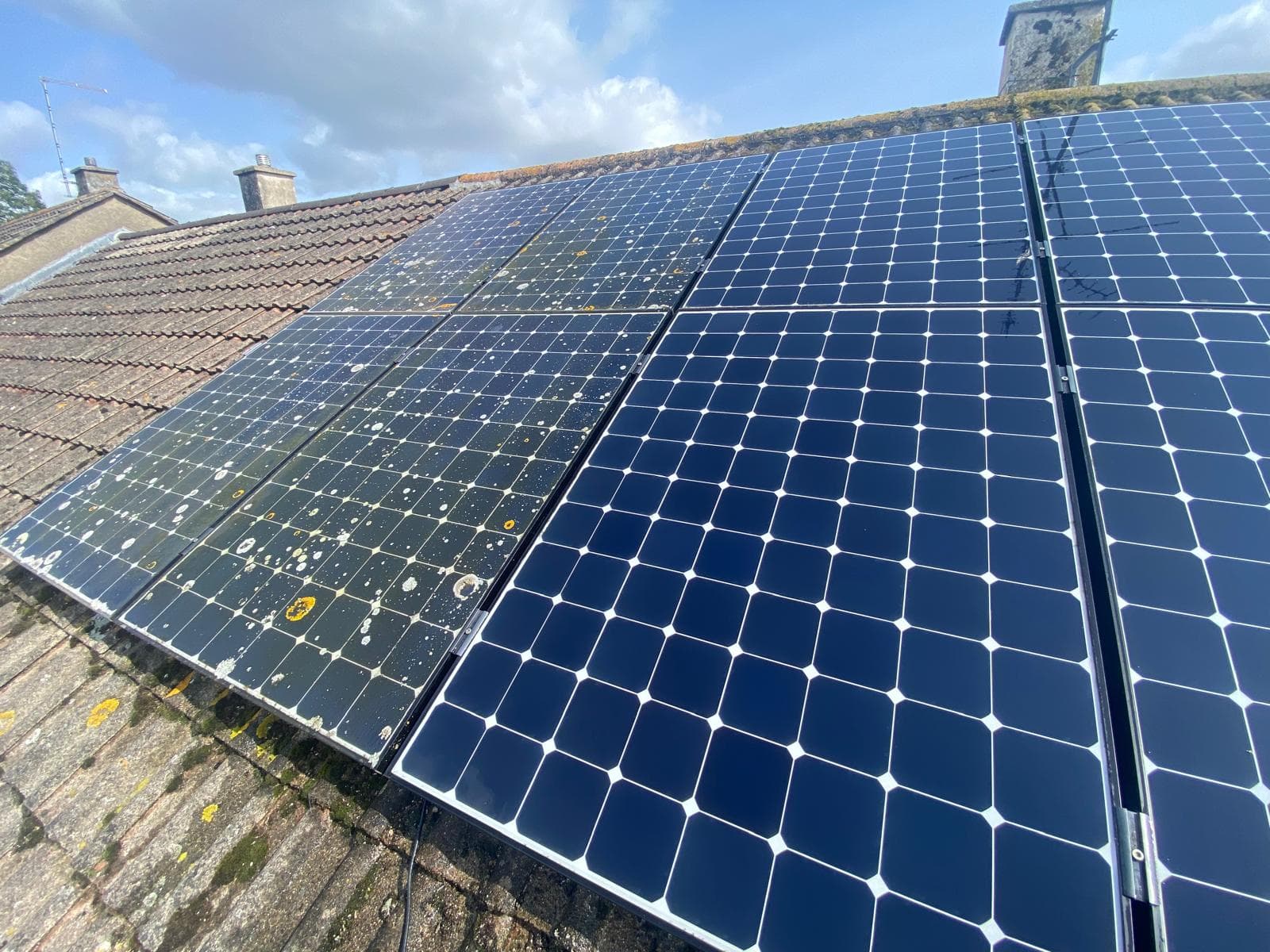 Solar panels on a tiled roof part-way through cleaning
